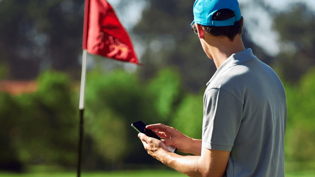 User tapping on phone on golf course